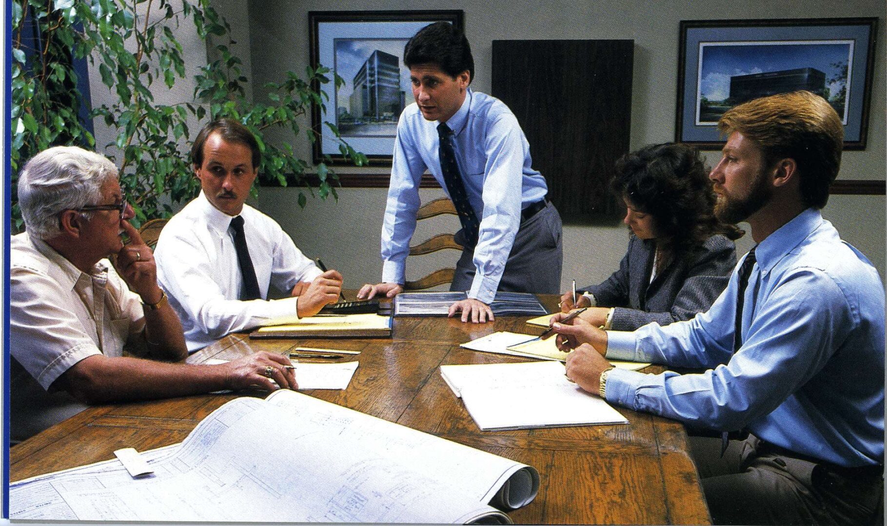 A group of people sitting at a table with papers.