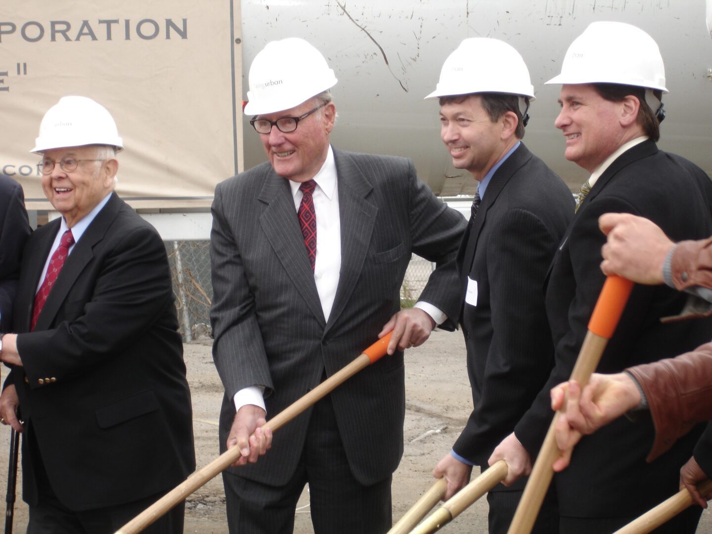 A group of people in suits and hard hats holding shovels.