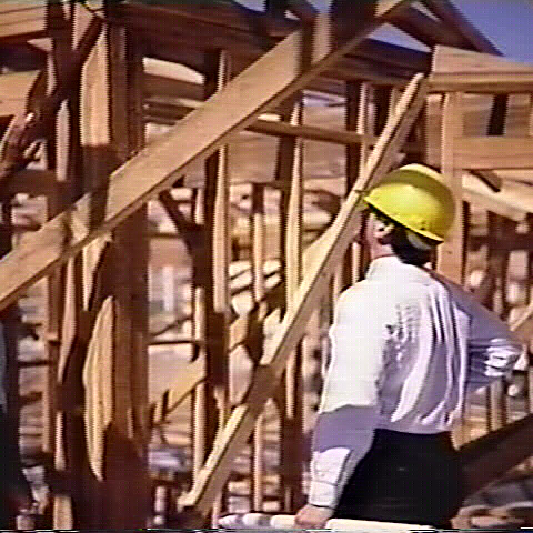 A man in a hard hat standing on top of a building.